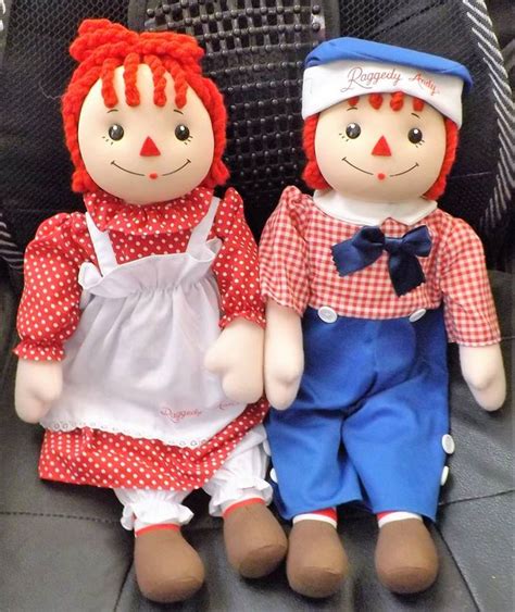 Two Dolls Sitting Next To Each Other On A Chair