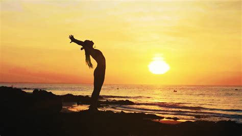 Silhouette Of Young Woman Is Doing Yoga Exercises On The Ocean Beach At Sunset Stock Video