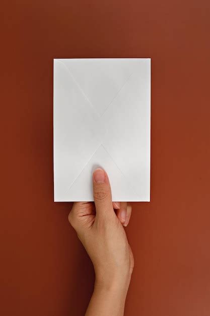 Premium Photo Cropped Hand Holding Envelope Over Brown Background