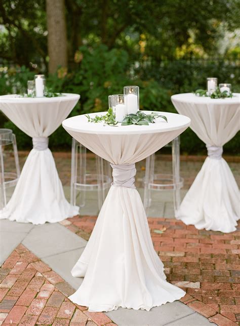 White Pillar Candles And Greenery Atop Cocktail Tables Outdoor Wedding Decorations Cocktail