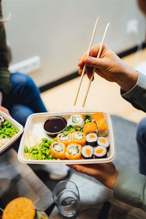 Toma Vertical De Una Persona Comiendo Sushi Para Llevar En Una Bandeja