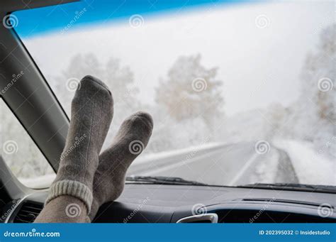 Female Feet In Woolen Socks On The Dashboard Of A Car In Winter