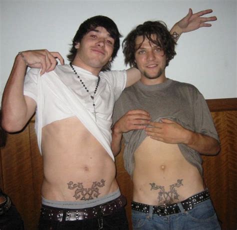 Two Men Standing Next To Each Other With Tattoos On Their Stomachs