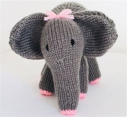 A Knitted Elephant With Pink Tusks On Its Head And Ears Sitting In