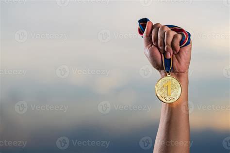 M O Segurando A Medalha De Ouro Contra O Fundo Do C U Nublado Do