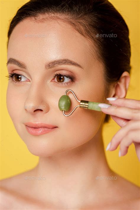 Portrait Of Beautiful Naked Woman Using Jade Roller On Face Isolated On