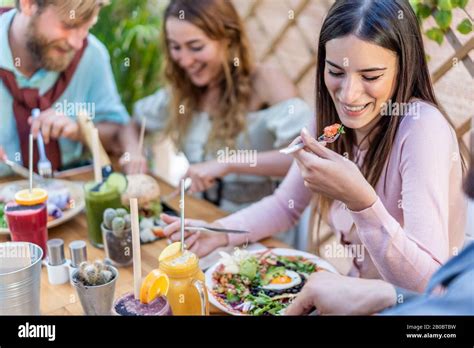 Young People Eating Brunch And Drinking Smoothie Bowl At Vintage Bar