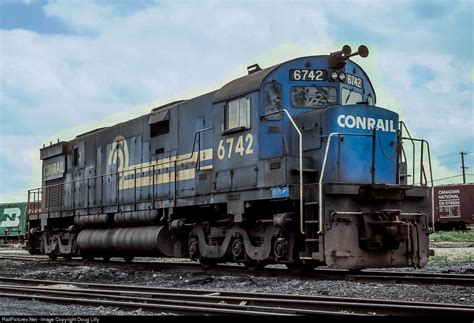 A Blue And Yellow Train Engine Sitting On The Tracks Next To Some Other