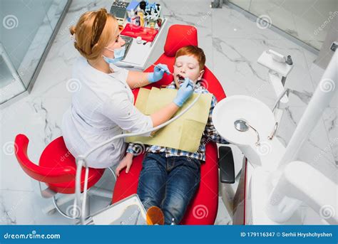 Pediatric Dentist Examining A Little Boys Teeth In The Dentists Chair At The Dental Clinic Stock