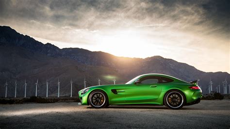 A Green Sports Car Parked In Front Of Mountains