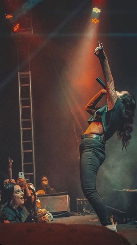 A Woman Is Performing On Stage With Her Arms In The Air