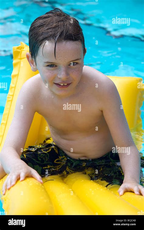 Happy Young Boy Relaxing At The Swimming Pool On A Yellow Lilo Stock