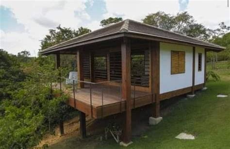 A Small House Sitting On Top Of A Lush Green Hillside