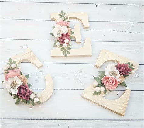 Three Wooden Letters Decorated With Flowers And Leaves