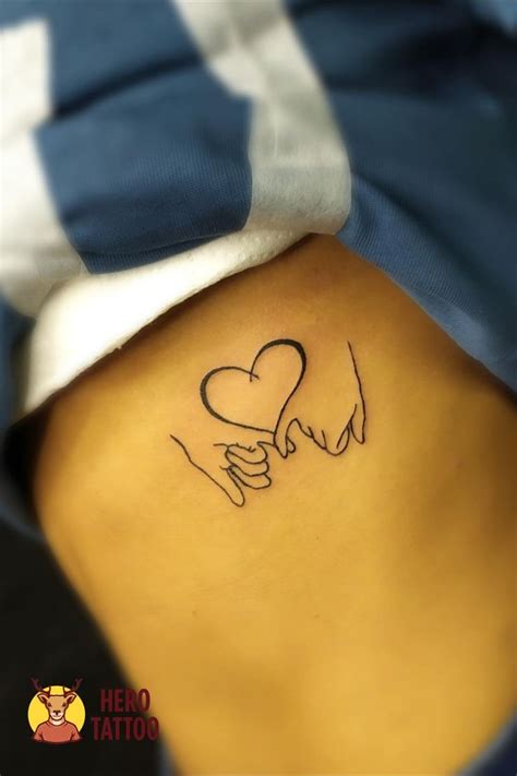 a woman's back with a tattoo on her stomach that has two hands holding ...