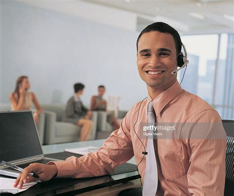 Male Receptionist Wearing Headset Sitting In Foreground Three