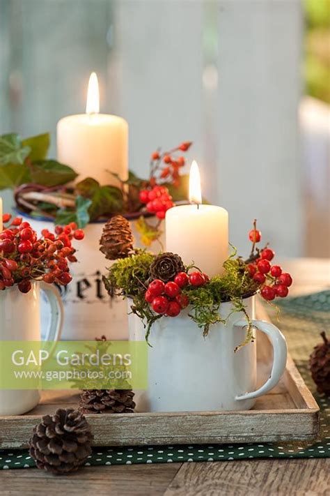 Three White Mugs Filled With Red Berries And Greenery Sit On A Tray