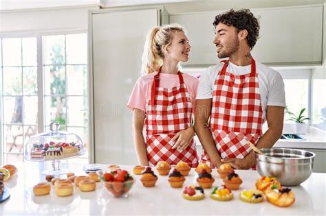 Couple Of Wife And Husband Cooking Pastries At The Kitchen Looking Away To Side With Smile On