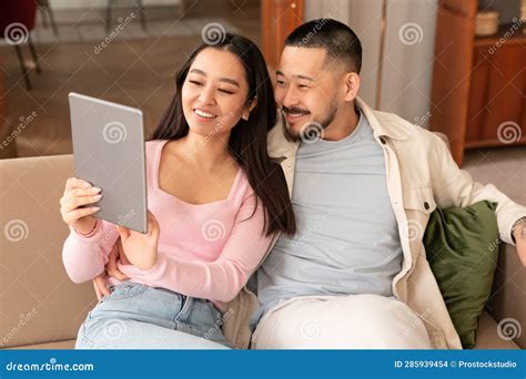 Japanese Husband And Wife Using Tablet Searching Websites At Home Stock