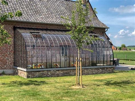 Greenhouse against wall with curved semicircular roof in wrought iron & glass