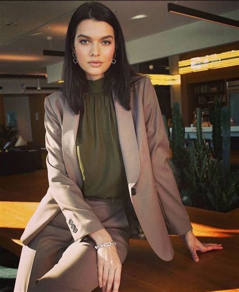 A Woman Sitting On Top Of A Wooden Table Wearing A Suit And Heels With