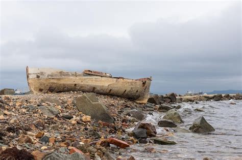 Premium Photo A Wrecked Boat On The Shore Next To Wharf The Boat Is