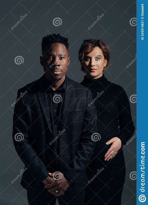 Young African Man And His Caucasian Pregnant Woman Stand Against Grey