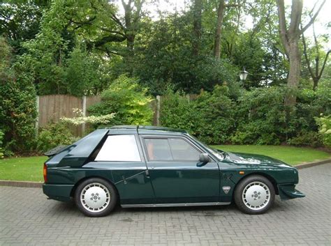 A Green Car Parked In Front Of Some Trees