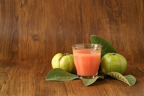 El Jugo De Guayaba Roja Se Sirve Sobre Un Fondo De Madera Con Rodajas