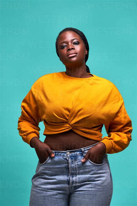 Unemotional Plump African American Female In Yellow Sweater Standing