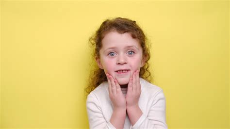 Little Girl Is Very Surprised Puts Her Hands To Her Head And Opens Her