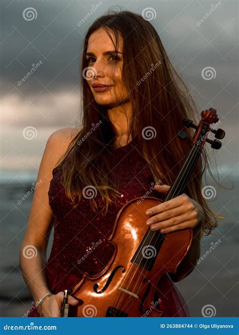 Portrait Of Attractive Caucasian Woman Holding Violin On The Beach