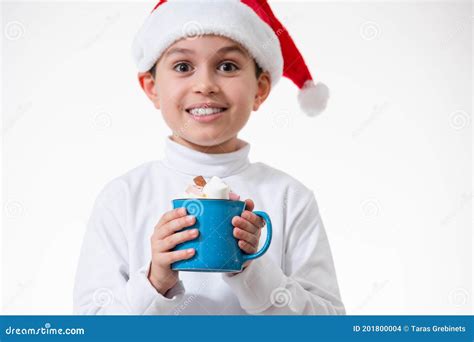 A Boy In A Red Santa Hat Smiles And Holds A Cup Of Marshmallows