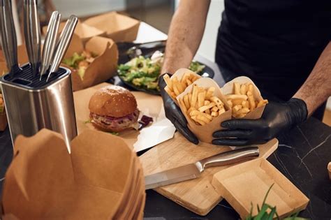 Premium Photo French Fries Vegetables And Burger Man Is Packing Food