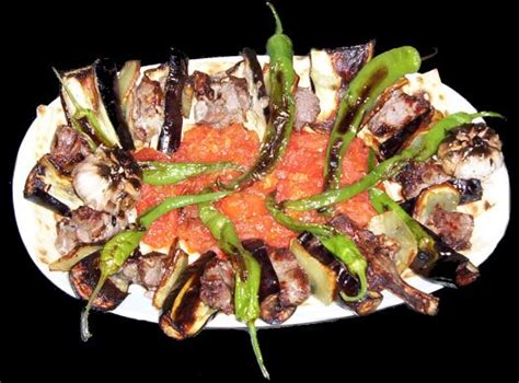 A White Plate Topped With Meat And Veggies On Top Of A Black Table