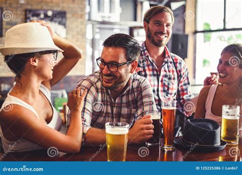 Pares Novos Que Bebem A Cerveja E Que Riem Junto Na Barra Foto De Stock