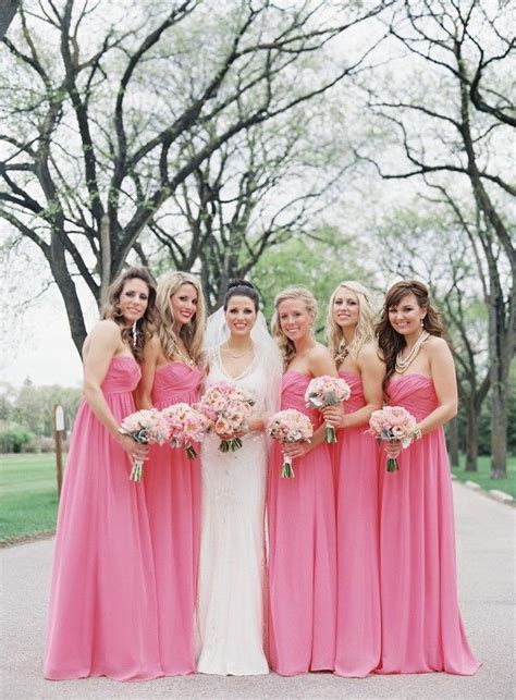 A Group Of Women In Pink Dresses Standing Next To Each Other With