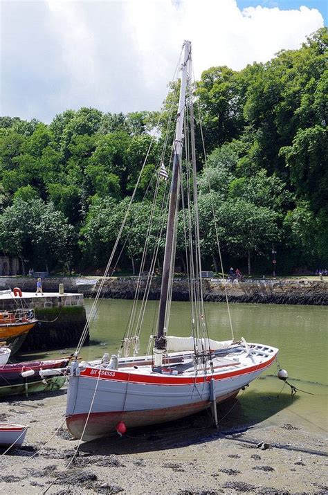 Two Boats Are Docked On The Shore Near Some Water And Trees In The Back