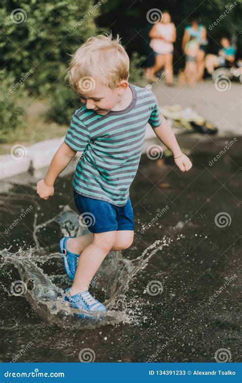 Little Boy Jumping In A Puddle In Summer Stock Image Image Of Baby