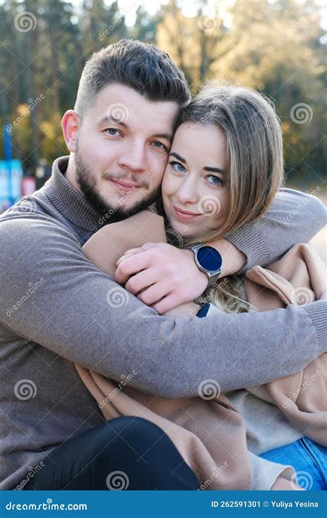 A Young Man Hugs A Woman By The Shoulders Couple Looking At Camera And