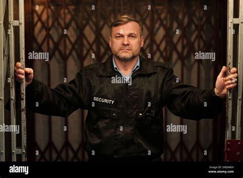 Serious Security Guard In Black Uniform Looking At Camera While Opening