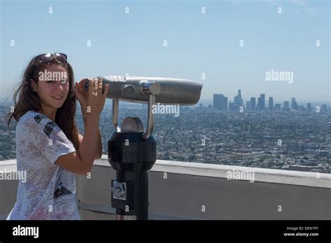 Female tourist using telescope to view Los Angeles from Griffith ...