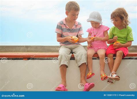 Crian As Menino E Duas Meninas Que Sentam Se Em Um Brach Foto De Stock