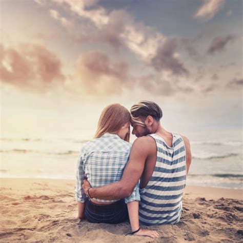 Loving Embraced Couple Sitting And Watching Sunset On Beach Stock