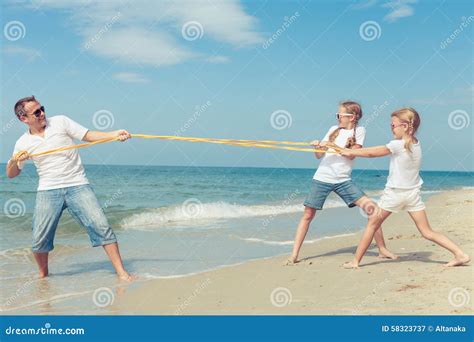 Pai E Filhas Que Jogam Na Praia No Tempo Do Dia Imagem De Stock