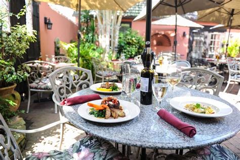 An Outdoor Dining Area With Tables Chairs And Umbrellas