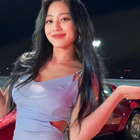 A Woman In A Blue Dress Standing Next To A Red Car