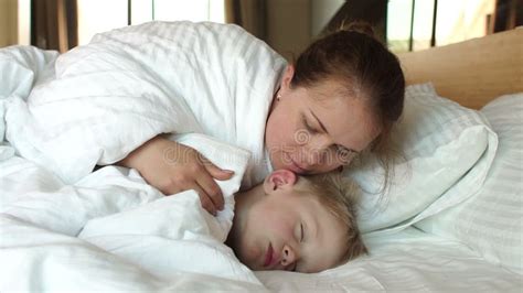 A Caring Mother Wakes Her Sleeping Son In The Morning In Bed Stock