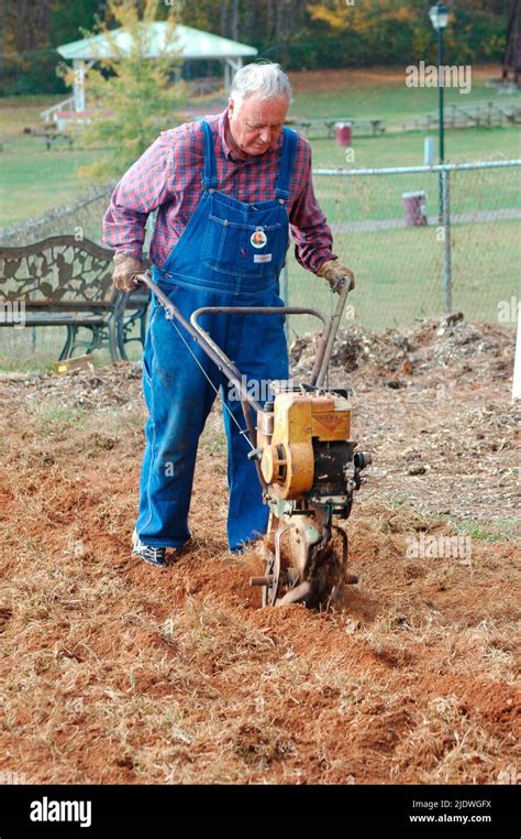 Men Roto Tilling A Lawn To Put In Garden With Tillers Front And Rear