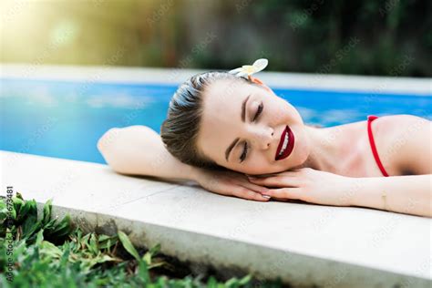 Beautiful Young Woman With Long Hair In The Red Swimsuit Keeps His Hands On The Edge A Pool In